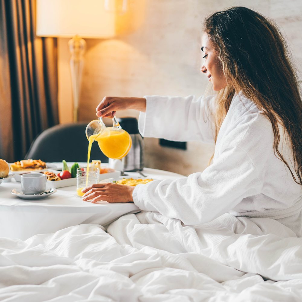 Woman eating breakfast in the hotel room. Room service breakfast in hotel room.